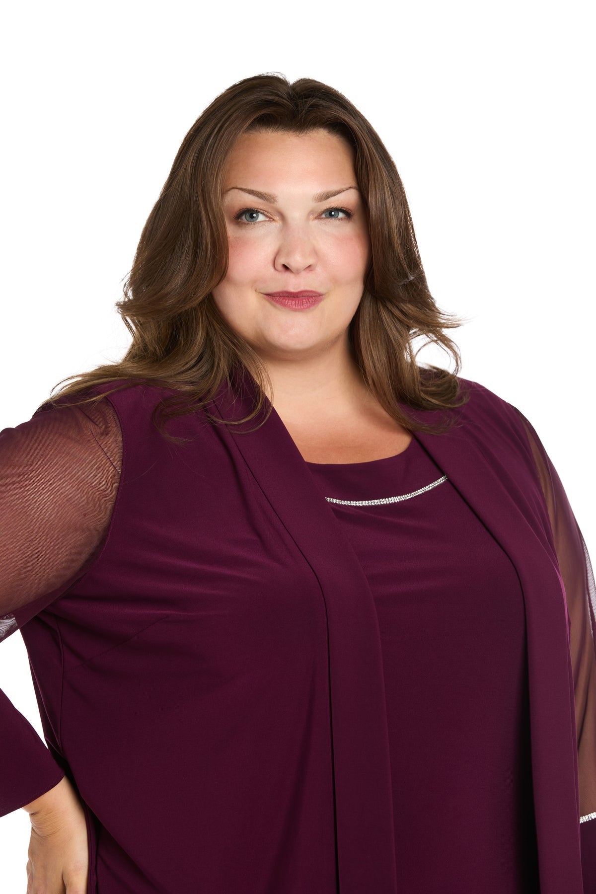 Woman with long brown hair wears the affordable R&M Richards 3747W Short Plus-Size Jacket Party Dress, featuring a burgundy top with sheer sleeves, standing against a white background and looking at the camera.